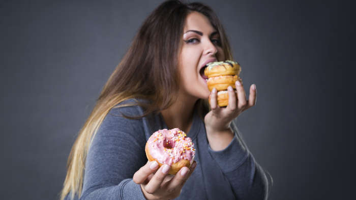 Tipps gegen Heißhunger wirken nicht, wenn die Fressattacke da ist. Frau mit Süßigkeiten